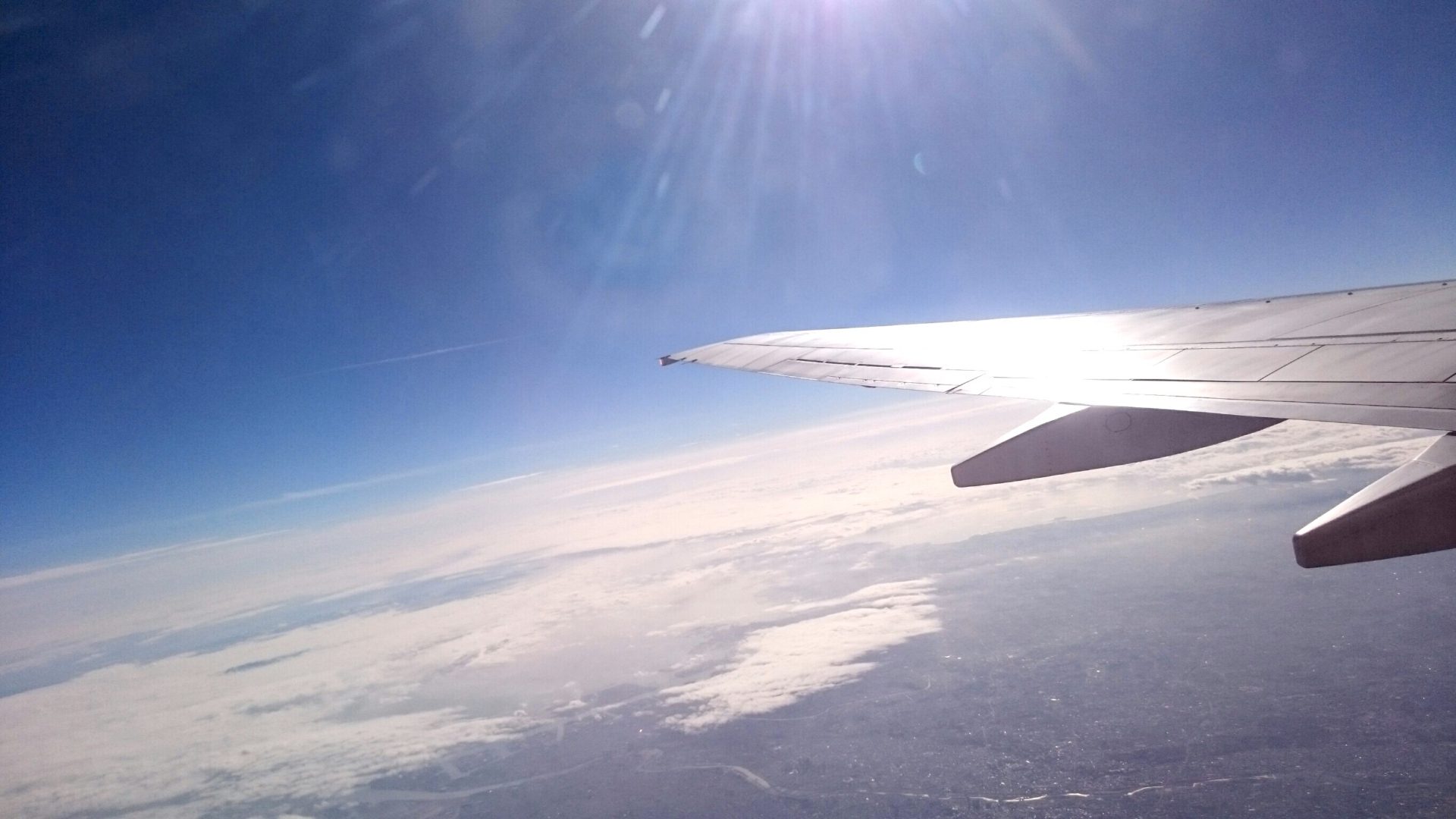 機内から撮影した太陽に照られさる飛行機の翼
